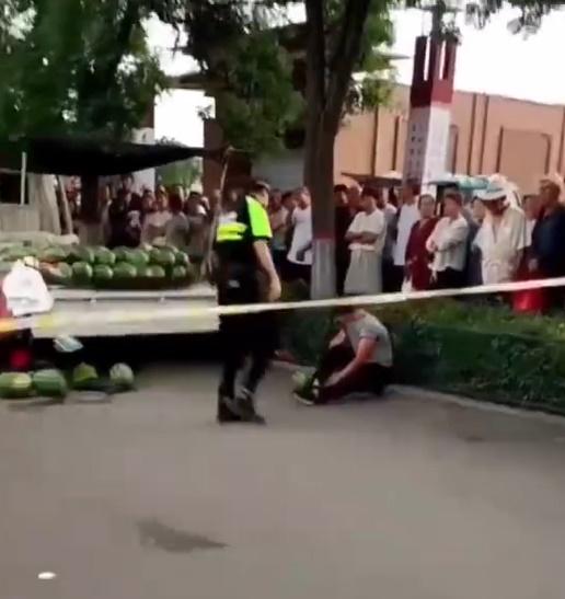 一名身穿淺色上衣男子坐在地上,一名婦人由警員帶走,許多民眾在場圍觀。(微博)