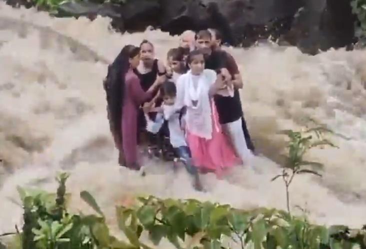 這家人受困暴漲溪水中的一塊岩石上,緊緊相擁。(X)