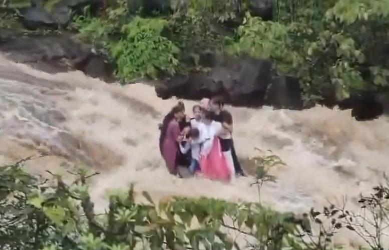 這家人受困暴漲溪水中的一塊岩石上,緊緊相擁。(X)