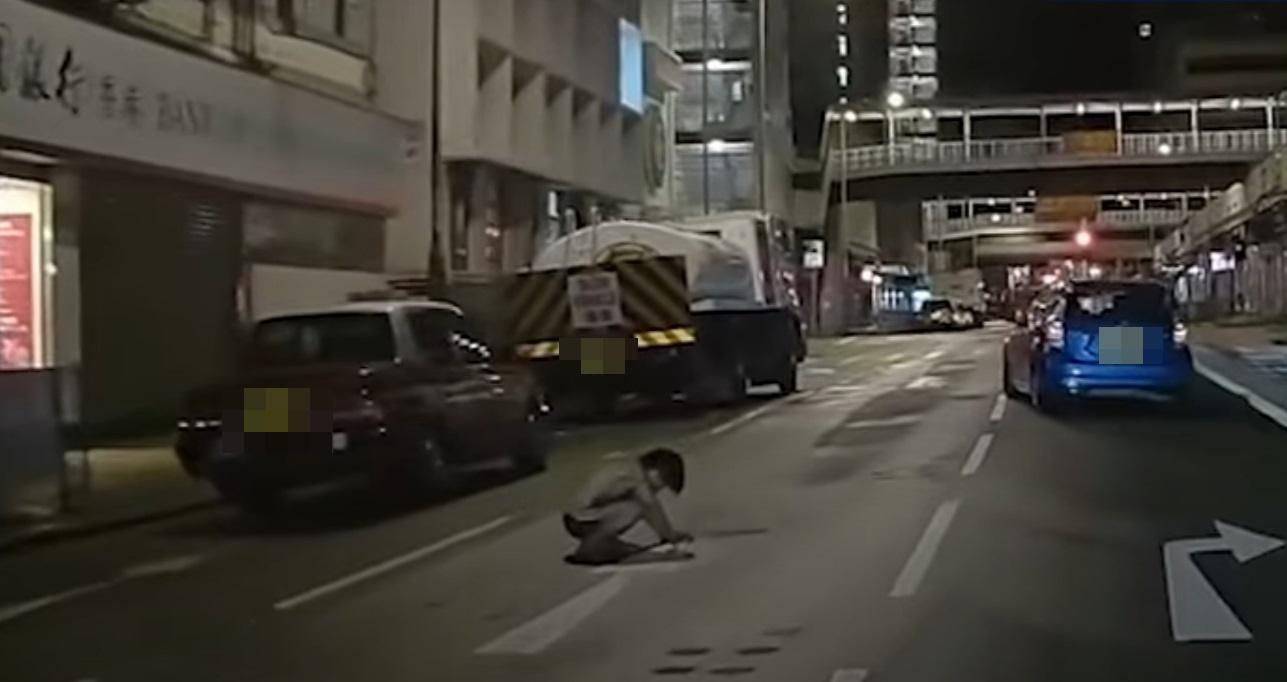 車Cam直擊|神秘男子晚間半蹲在馬路上。(網片截圖)