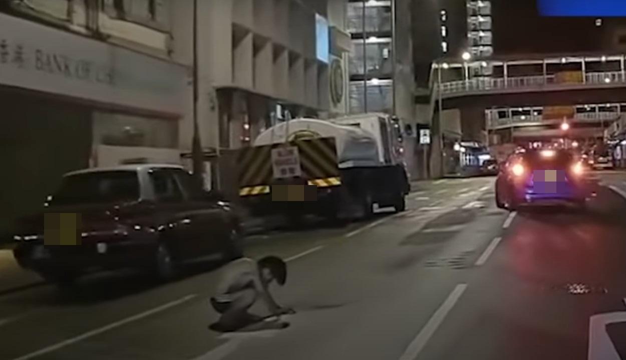 車Cam直擊|神秘男子晚間半蹲在馬路上。(網片截圖)