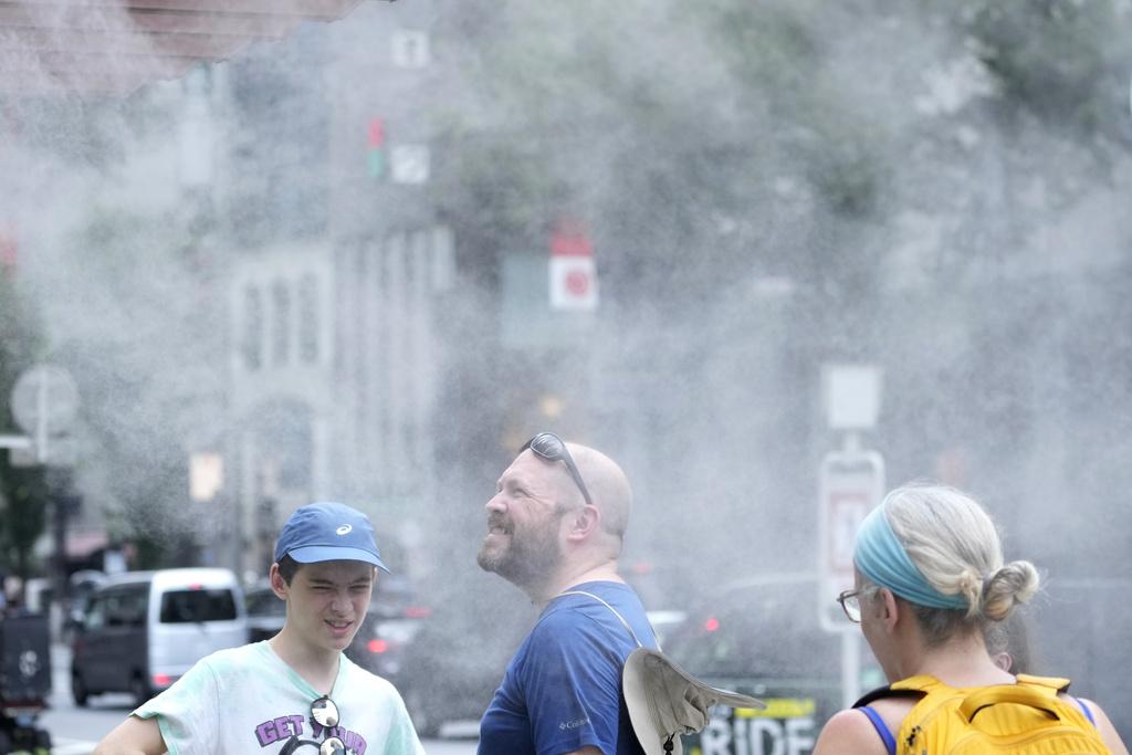 東京周四酷熱,有外籍人士享受街上水霧的涼意。(美聯社)
