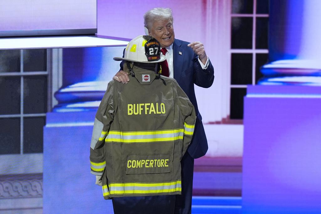 台上展示了遇刺案中遇難的水牛城鎮前義務消防隊長Corey Comperatore的消防頭盔制服,特朗普於台上又親吻其頭盔(美聯社)