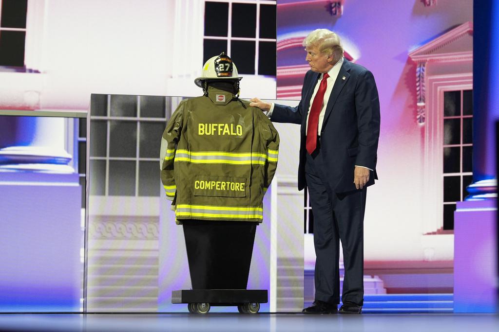 台上展示了遇刺案中遇難的水牛城鎮前義務消防隊長Corey Comperatore的消防頭盔制服,特朗普於台上又親吻其頭盔(美聯社)