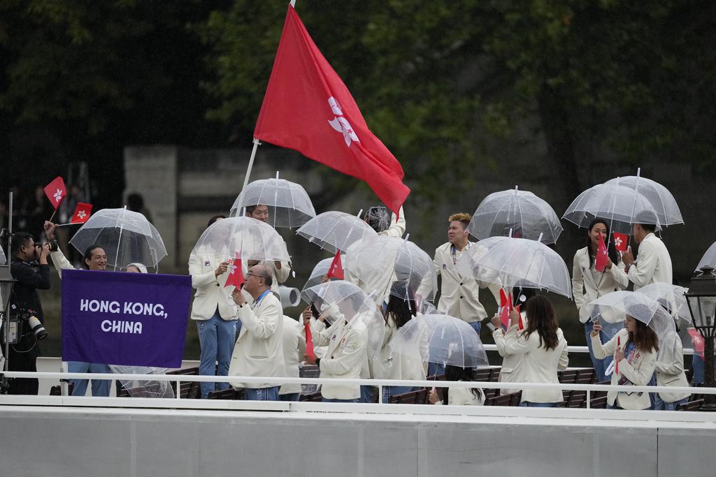 開幕禮現場有雨,故港隊運動員巡遊時都需要撐傘避雨。(美聯社)