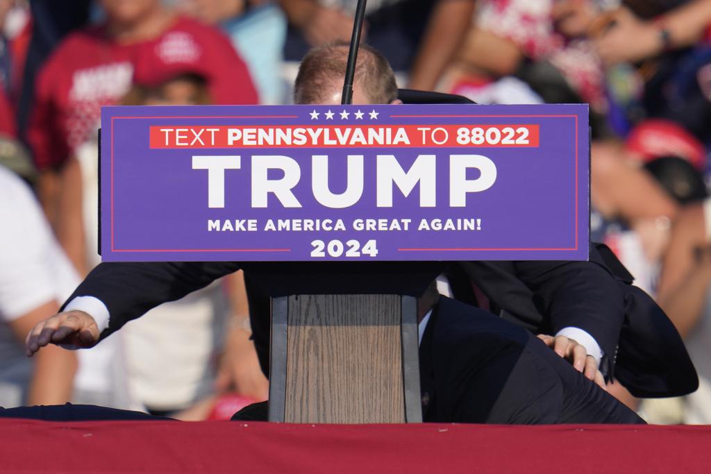 特朗普中槍倒地,由特勤人員掩護。(美聯社)