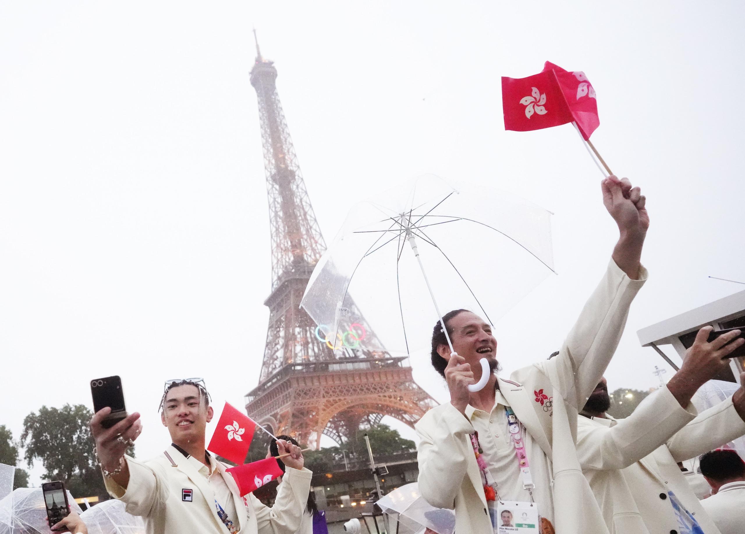 開幕禮現場有雨,故港隊運動員巡遊時都需要撐傘避雨。(新華社)