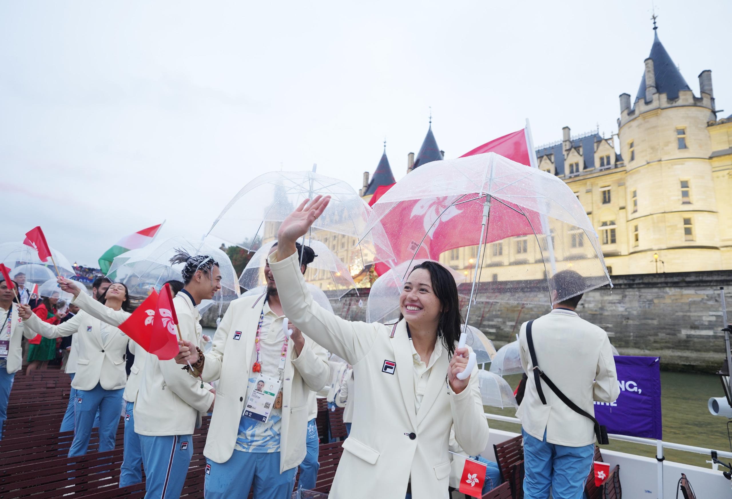 開幕禮現場有雨,故港隊運動員巡遊時都需要撐傘避雨。(新華社)