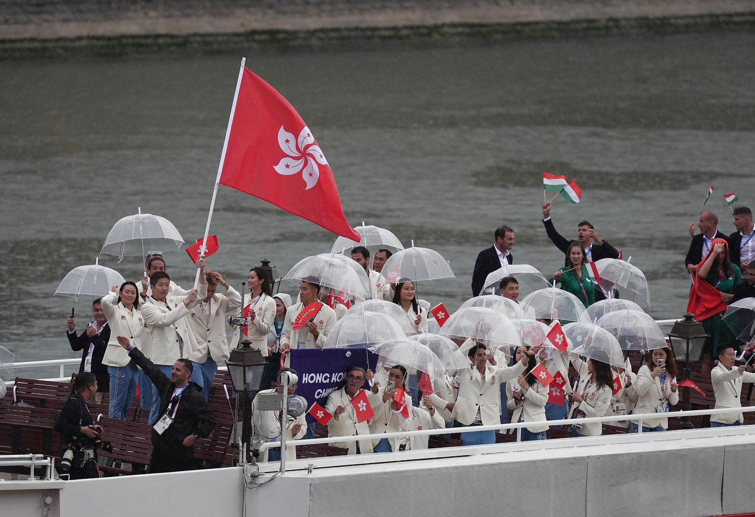 開幕禮現場有雨,故港隊運動員巡遊時都需要撐傘避雨。(新華社)
