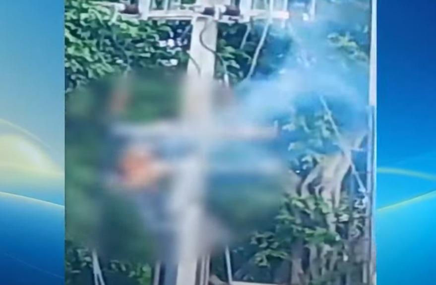 穿橙衣的工人在電線桿上觸電,全身冒煙,十分嚇人。(互聯網)