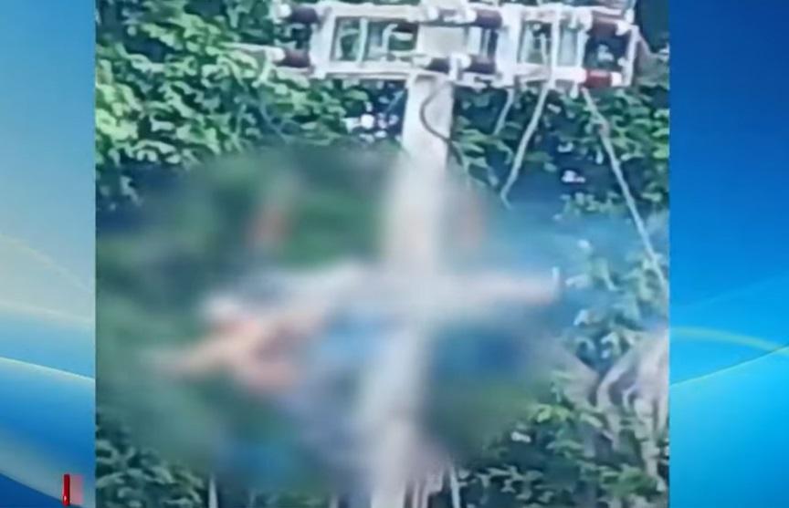 穿橙衣的工人在電線桿上觸電,身體冒煙,試著自救,但身體被安全帶綁著。(互聯網)