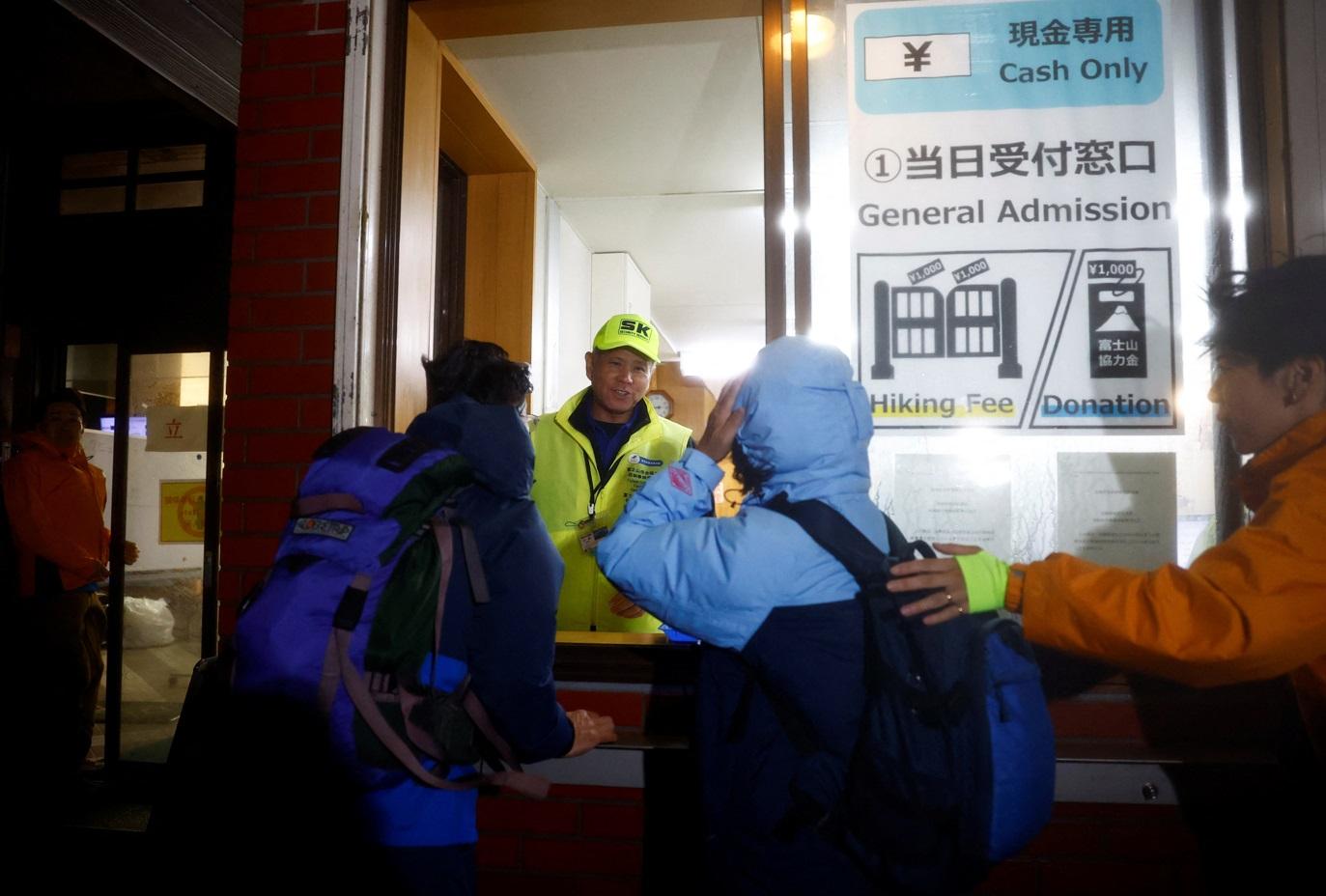 民眾在富士吉田口登山步道閘門前領取手帶。(路透社)