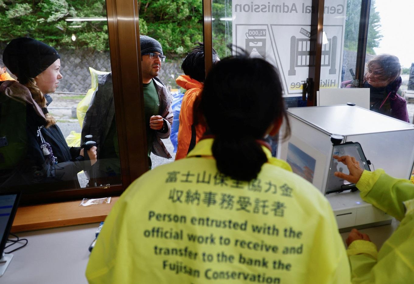 閘門登記處工作人員向外籍登山客派發手帶。(路透社)