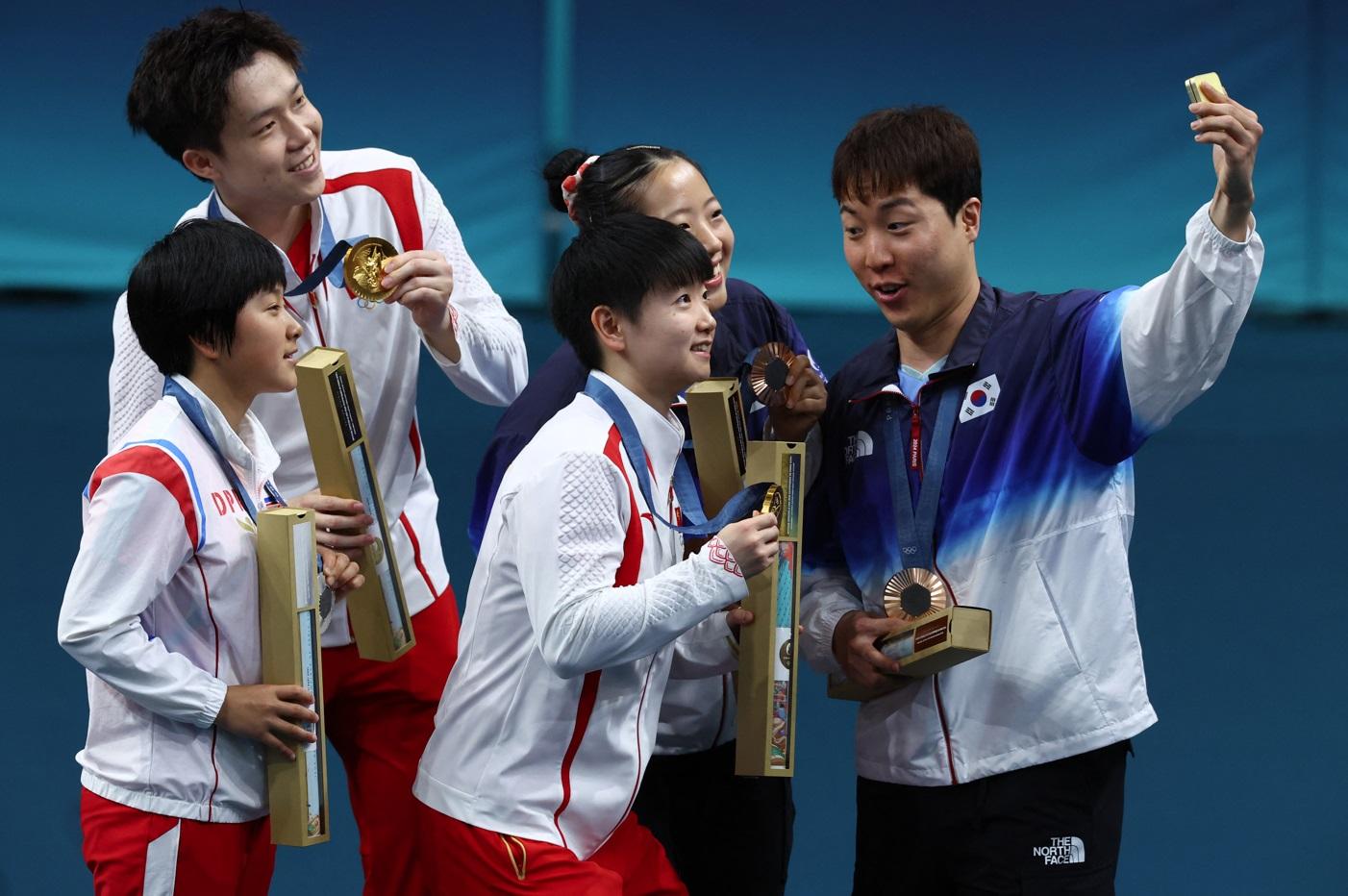 南韓選手林鐘勳拿手機拍攝,各人笑對鏡頭,留住珍貴一刻。(路透社)