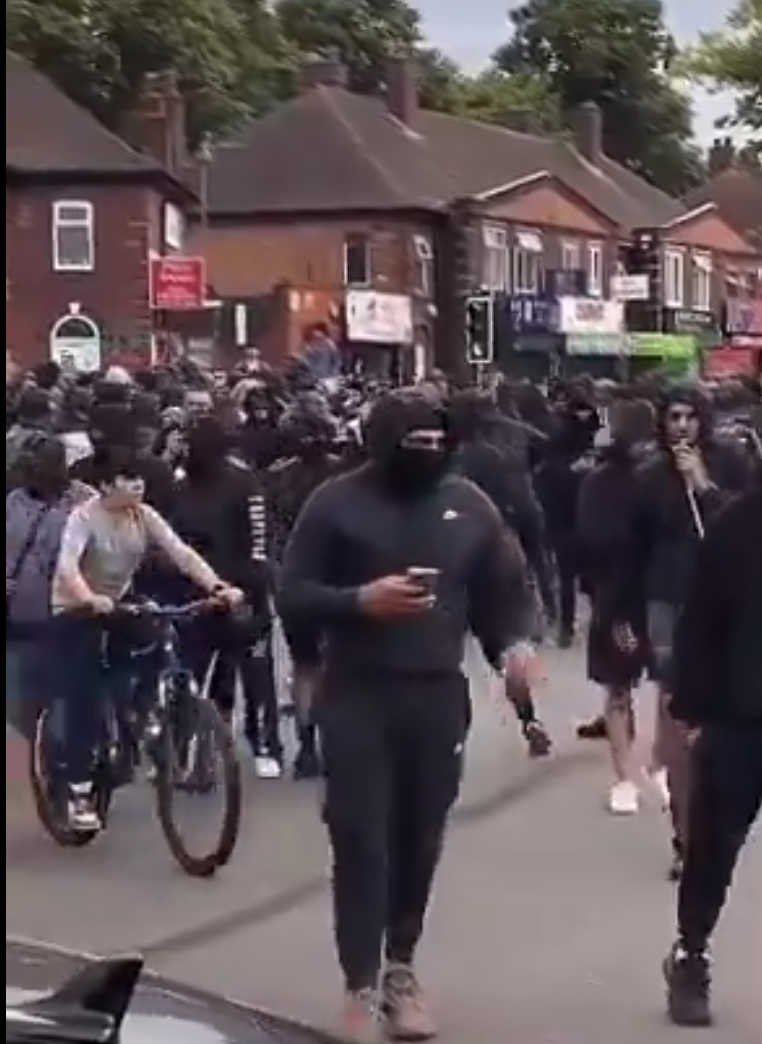 英國第二大城市伯明翰周一晚流傳會有右翼團體發起示威,大批穿黑衫民眾於一間連鎖快餐店外聚集戒備(影片截圖)