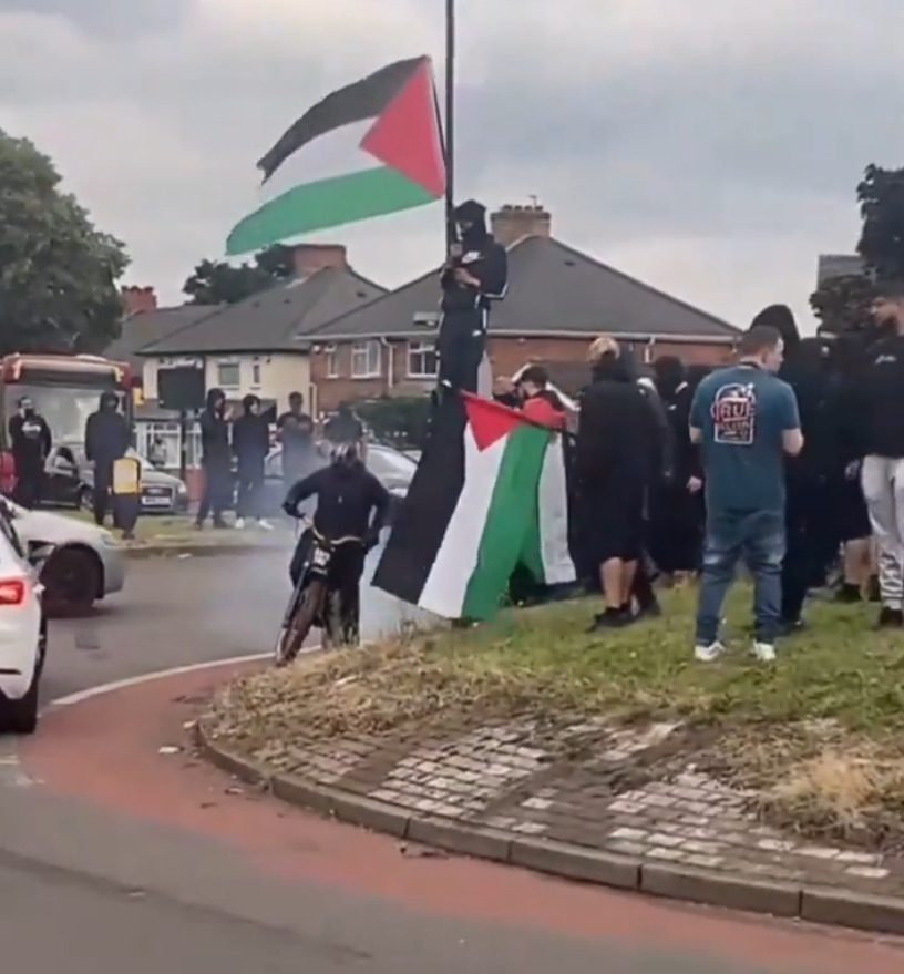 伯明翰周一晚流傳會有右翼團體發起示威,大批穿黑衫民眾於一間連鎖快餐店外聚集戒備,部分人手持巴勒斯坦旗(影片截圖)