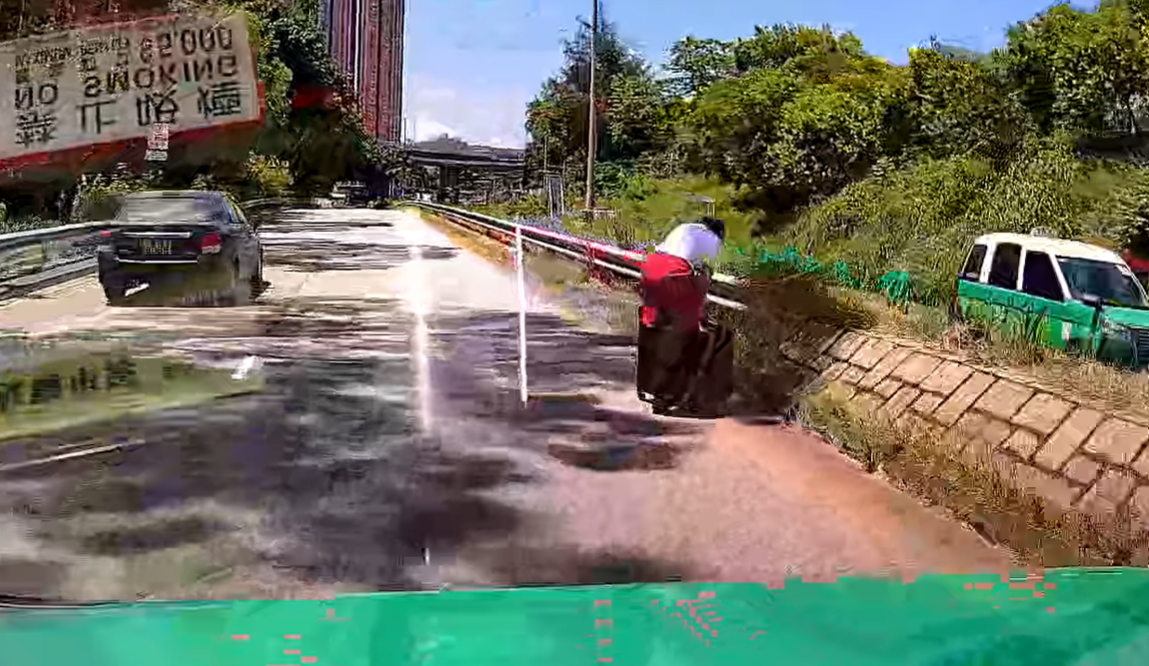 一輛綠色的士於屯門青雲路行駛期間,前方突出現一名帶行李喼的國泰女空姐。(影片截圖)