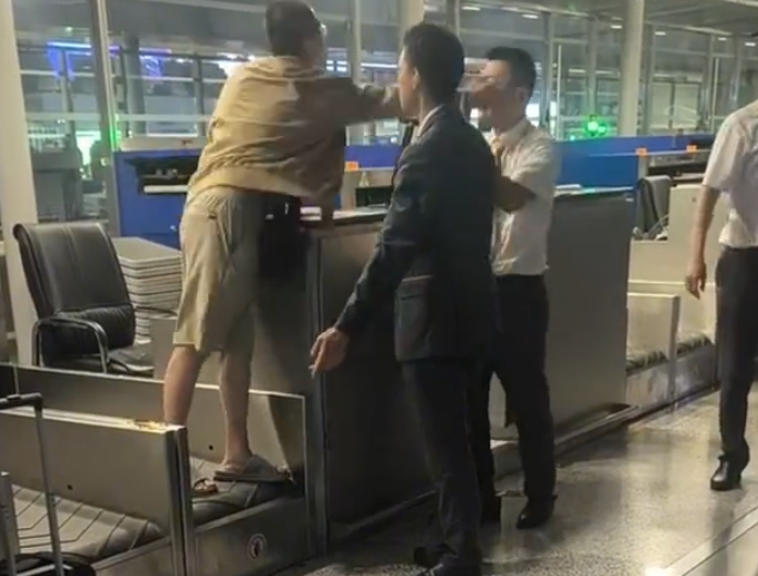 上海浦東機場有乘客因遲到未能乘搭原定航班,在航空公司櫃檯情緒失控,毆打機場地勤人員,遭公安行政拘留。(影片截圖)