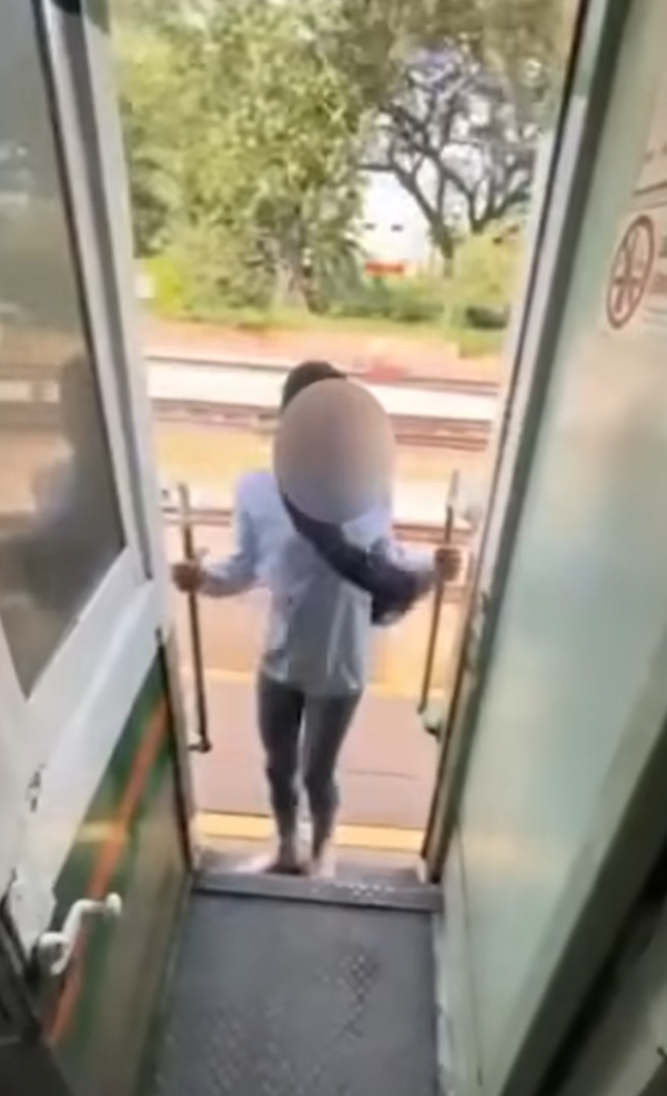 該名女子在火車行駛期間站在敞開的車門梯級,雙手扶住欄杆身體向後傾,及後頭部撞到車外一條柱,她一度失平衡但仍緊握扶手。(影片截圖)