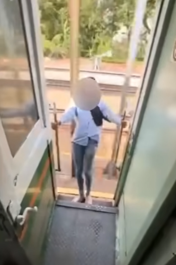 該名女子在火車行駛期間站在敞開的車門梯級,雙手扶住欄杆身體向後傾,及後頭部撞到車外一條柱,她一度失平衡但仍緊握扶手。(影片截圖)