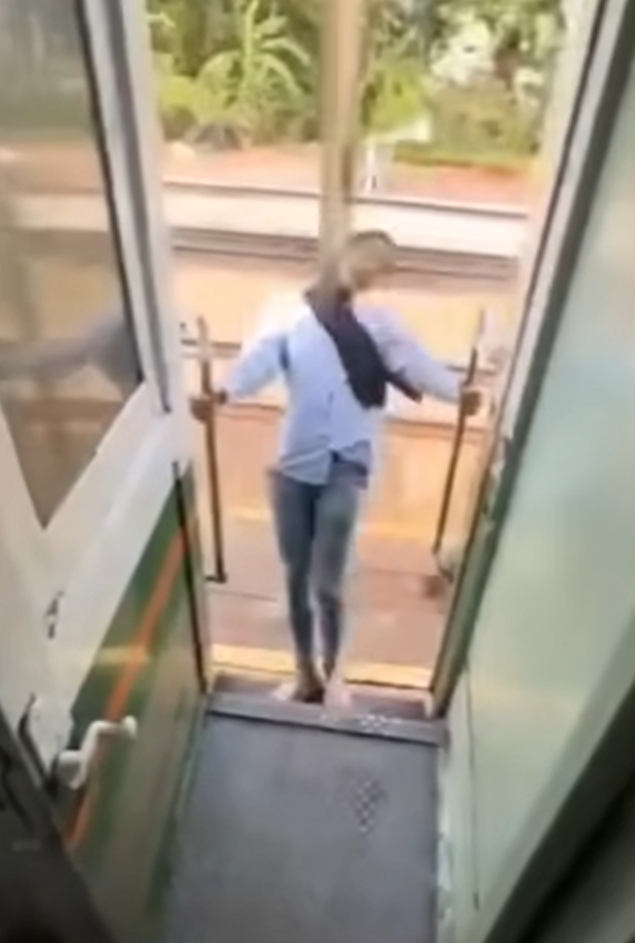 該名女子在火車行駛期間站在敞開的車門梯級,雙手扶住欄杆身體向後傾,及後頭部撞到車外一條柱,她一度失平衡但仍緊握扶手。(影片截圖)