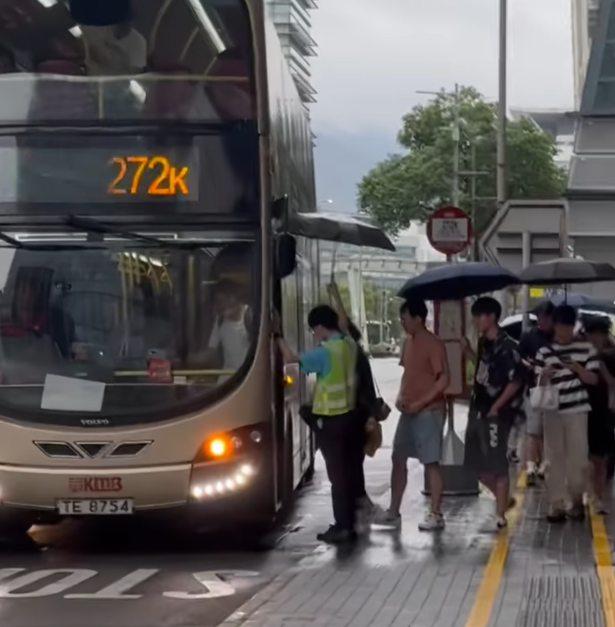 在科學園272K線往大學站的車站,大批乘客正排隊準備上車,該名九巴職員於車門「擔遮」,方便乘客提早收傘上車,亦避免遭淋濕。(社交平台Threads)