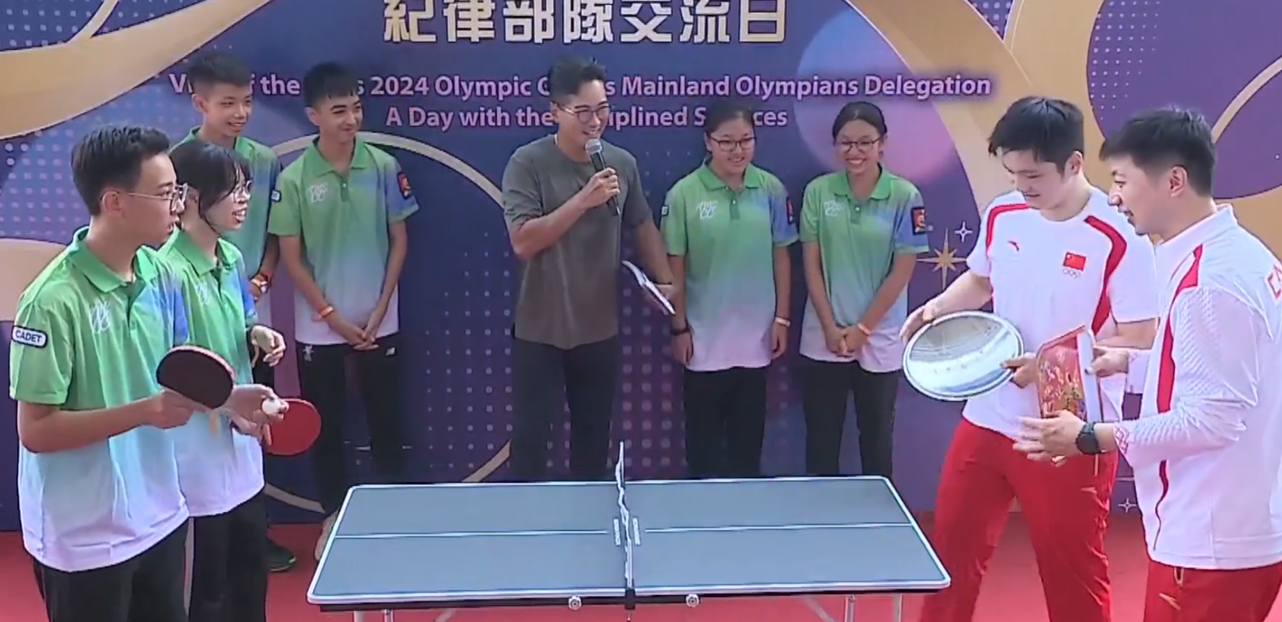 兩名乒乓球選手馬龍、樊振東與青少年較技,為了讓賽,球拍更換成盤子、煲蓋、鑊鏟(電視畫面)