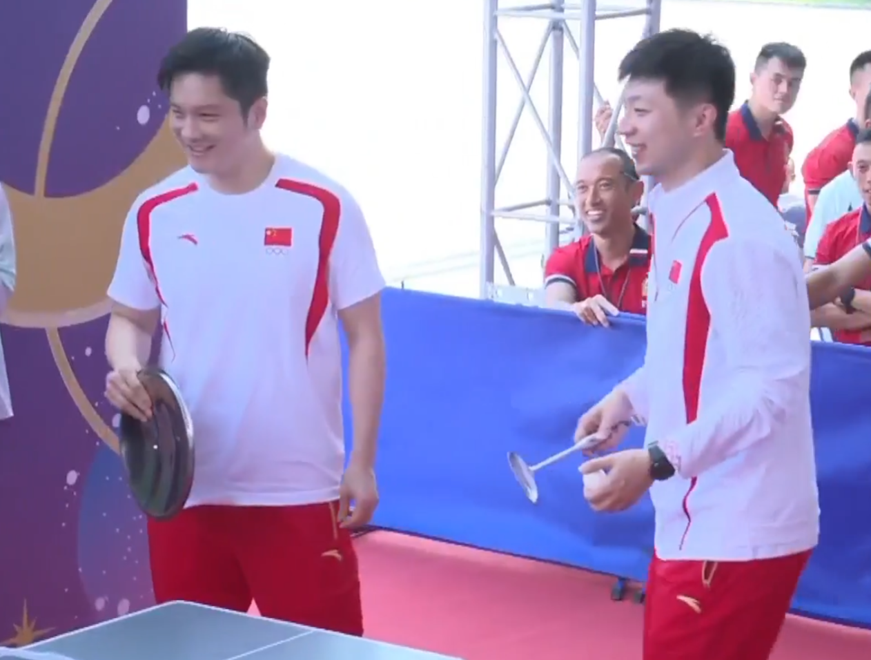 兩名乒乓球選手馬龍、樊振東與青少年較技,為了讓賽,球拍更換成盤子、煲蓋、鑊鏟(電視畫面)