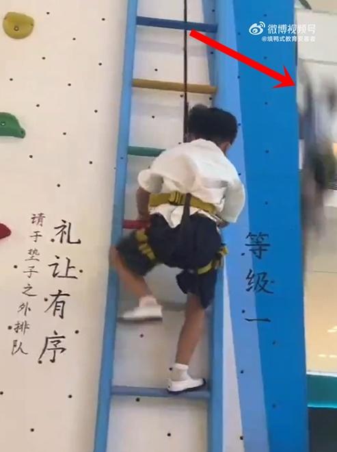 網上影片顯示,一名小孩身上綁著安全繩正在進行攀爬。突然旁邊有人隨著繩子一起掉落。(微博)