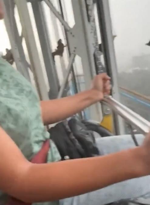 拍攝者身旁的女伴雙手緊握韆鞦鐵鏈。(X)