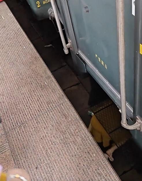 從月台與火車縫隙間,可見一名身穿黃色裙的女子在火車底。(微博)