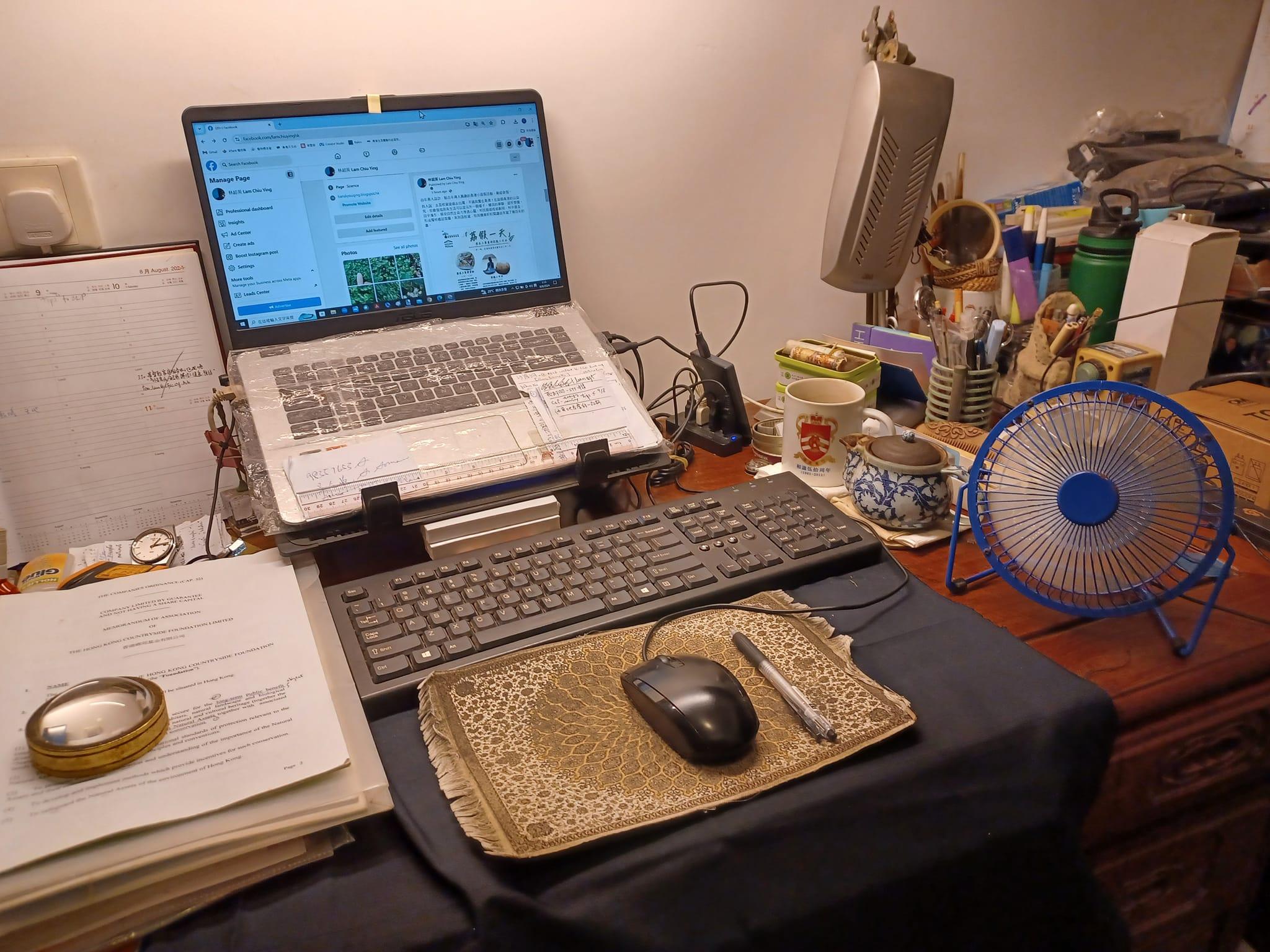 林超英在Facebook專頁發帖,可見其書枱放了文件及手機電腦,旁邊仲有一把USB小風扇