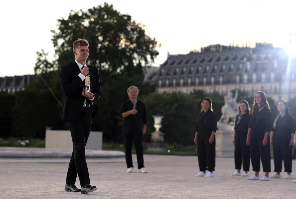 在今屆奧運為法國贏得四金一銅游泳獎牌的泳手馬桑,身穿黑西裝手持聖火揭開閉幕禮的序幕。(美聯社)