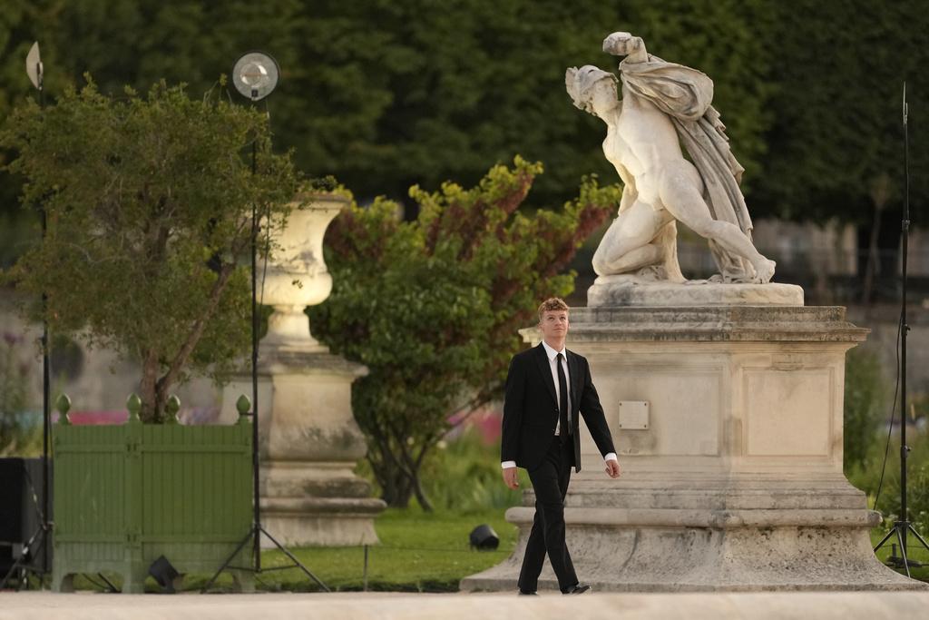 在今屆奧運為法國贏得四金一銅游泳獎牌的泳手馬桑,身穿黑西裝手持聖火揭開閉幕禮的序幕。(美聯社)