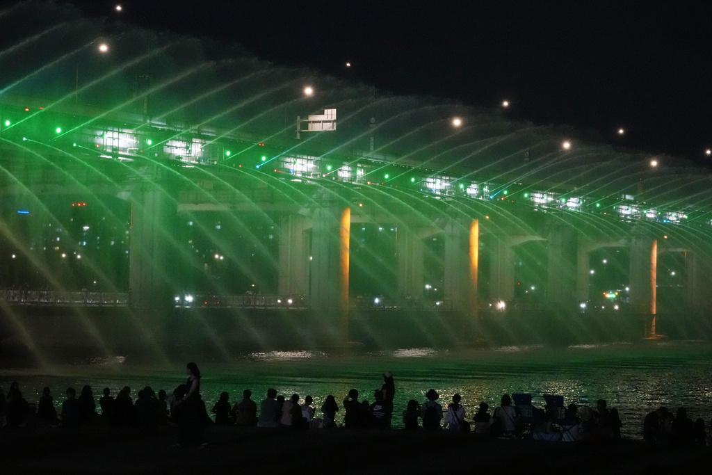 不少民眾上周五在首爾盤浦大橋月光彩虹噴泉旁,一邊觀賞美景一邊降溫。(美聯社)