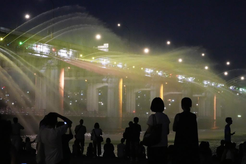 不少民眾上周五在首爾盤浦大橋月光彩虹噴泉旁,一邊觀賞美景一邊降溫。(美聯社)