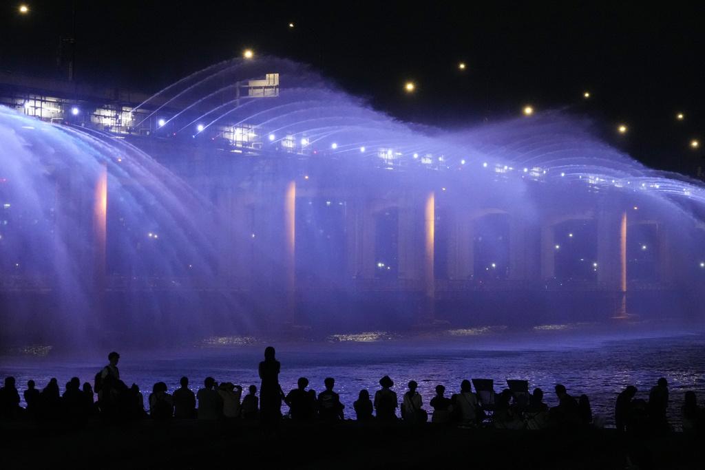 不少民眾上周五在首爾盤浦大橋月光彩虹噴泉旁,一邊觀賞美景一邊降溫。(美聯社)