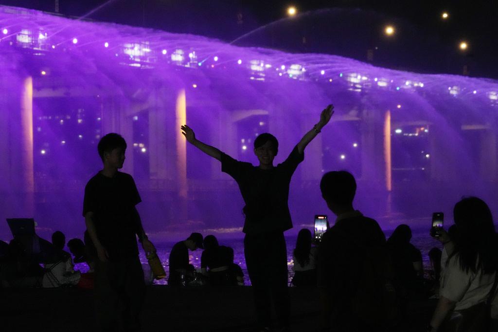 不少民眾上周五在首爾盤浦大橋月光彩虹噴泉旁,一邊觀賞美景一邊降溫。(美聯社)