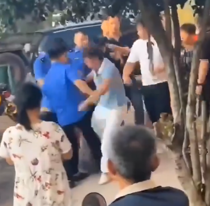 江西省撫州市東鄉區一間特色粉店門前,多名身穿城管制服的人員,圍毆倒地的兩名店主。(影片截圖)