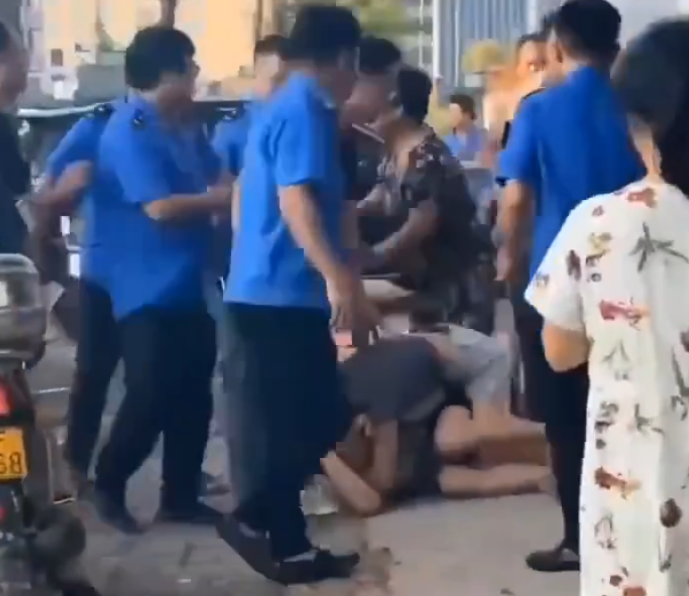 江西省撫州市東鄉區一間特色粉店門前,多名身穿城管制服的人員,圍毆倒地的兩名店主。(影片截圖)