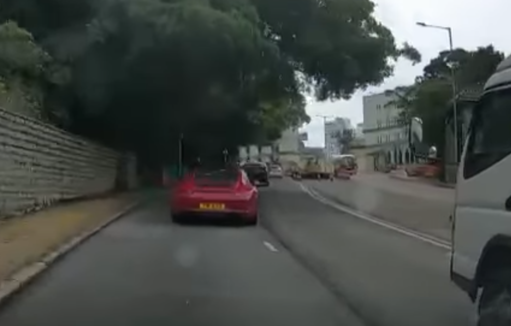 港島薄扶林道近瑪麗醫院路段一名男子推着需坐輪椅的長者於路邊「慢步」,與車輛驚險擦身而過,Cam主發現後即時響咹煞車爆粗,大罵男子行為危險。(影片截圖)