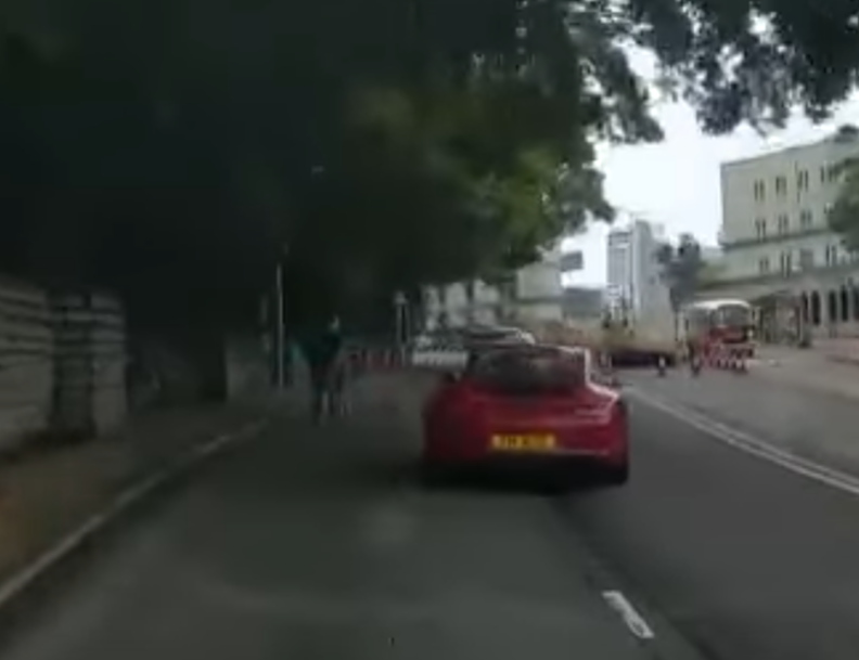 港島薄扶林道近瑪麗醫院路段一名男子推着需坐輪椅的長者於路邊「慢步」,與車輛驚險擦身而過,Cam主發現後即時響咹煞車爆粗,大罵男子行為危險。(影片截圖)