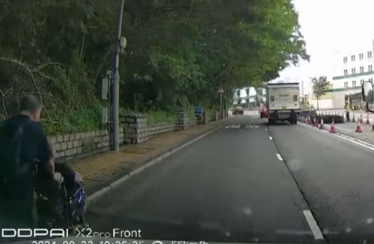 港島薄扶林道近瑪麗醫院路段一名男子推着需坐輪椅的長者於路邊「慢步」,與車輛驚險擦身而過,Cam主發現後即時響咹煞車爆粗,大罵男子行為危險。(影片截圖)