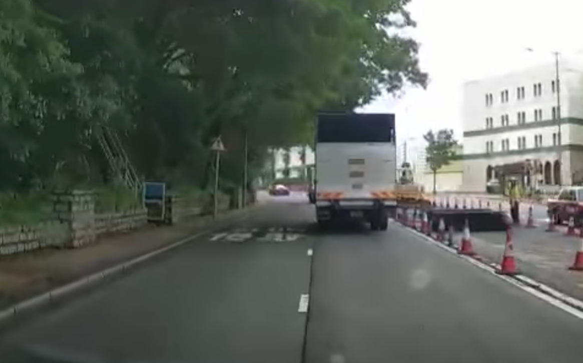 港島薄扶林道近瑪麗醫院路段一名男子推着需坐輪椅的長者於路邊「慢步」,與車輛驚險擦身而過,Cam主發現後即時響咹煞車爆粗,大罵男子行為危險。(影片截圖)