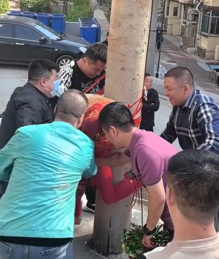 其間新娘喊叫掙扎但無人理會,疑似新郎手持鮮花用手攙扶著新娘,未有阻止眾人行為。(影片截圖)