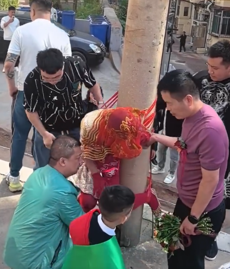 其間新娘喊叫掙扎但無人理會,疑似新郎手持鮮花用手攙扶著新娘,未有阻止眾人行為。(影片截圖)