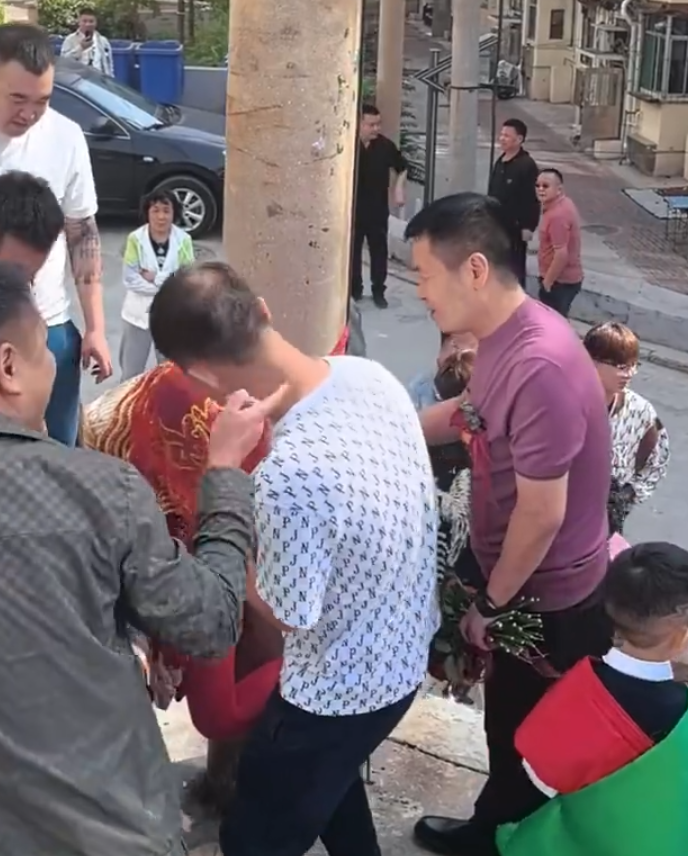 其間新娘喊叫掙扎但無人理會,疑似新郎手持鮮花用手攙扶著新娘,未有阻止眾人行為。(影片截圖)