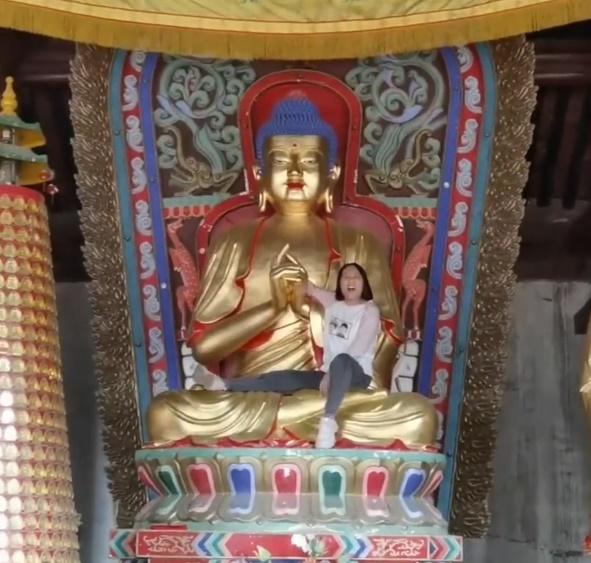 女子突然衝到佛像台座強行爬上佛像大喊大叫。(微博)