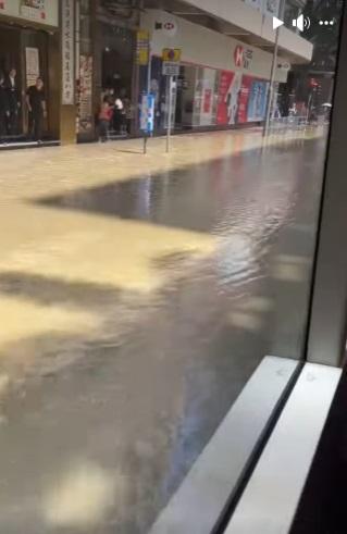 有巿民被迫站在店舖門外暫避,亦有人選擇涉水而行。(網片截圖)