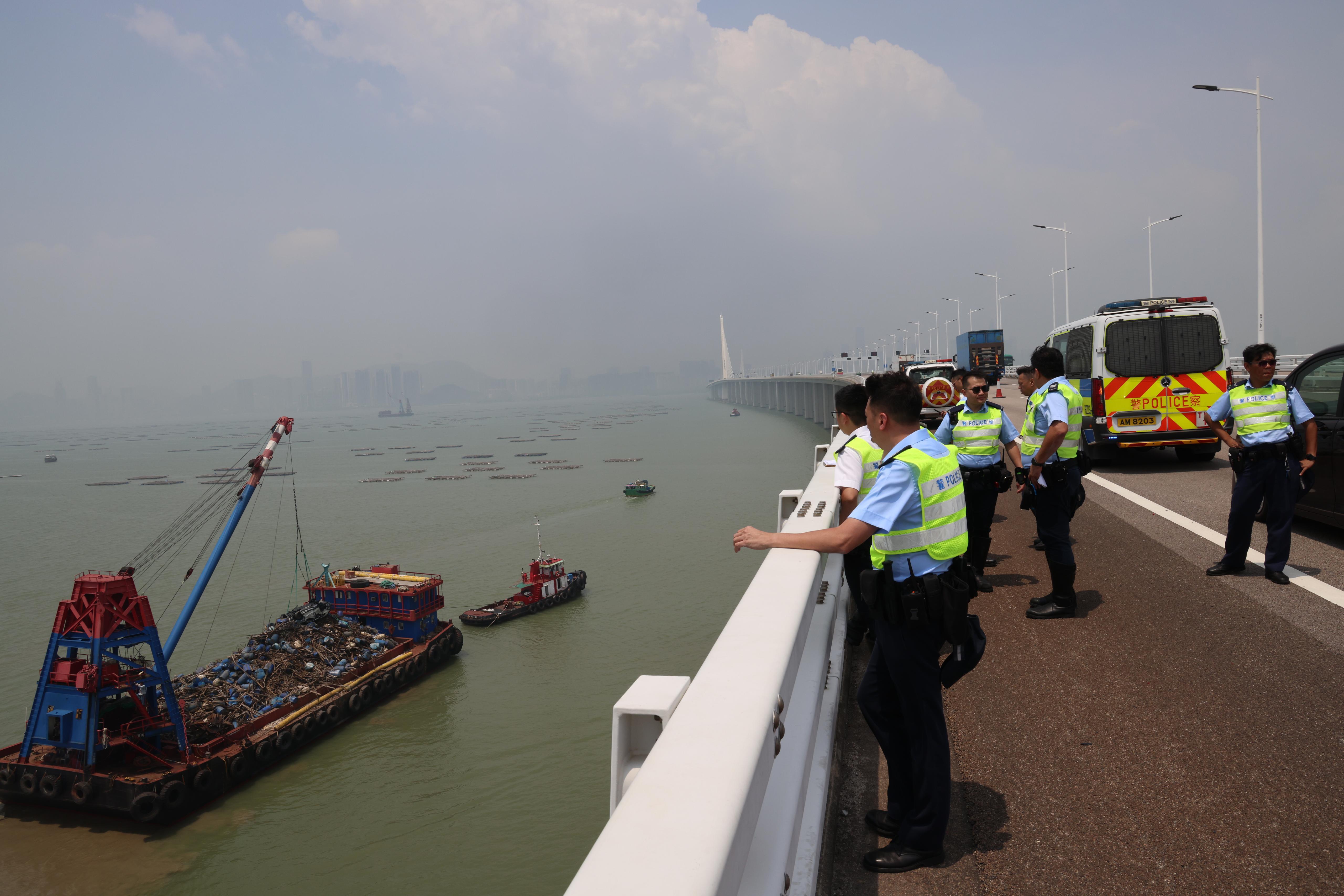 吊臂躉船在大橋附近的位置,用鋼纜把私家車由海中吊起,放上躉船運走。